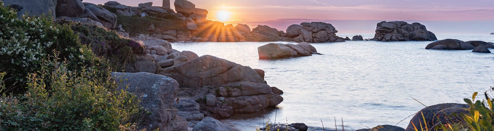 a beautiful sunset over the ocean and rocks