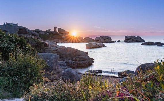 a beautiful sunset over the ocean and rocks